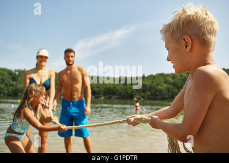 Family and kids at a lake playing tug of war on ther summer holiday Stock Photo