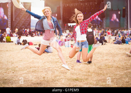 Teenage girls, music festival, jumping, in front of stage Stock Photo