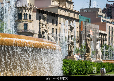 Stone statues standing beside water fountain in Plaça de Catalunya in Barcelona, Spain Stock Photo
