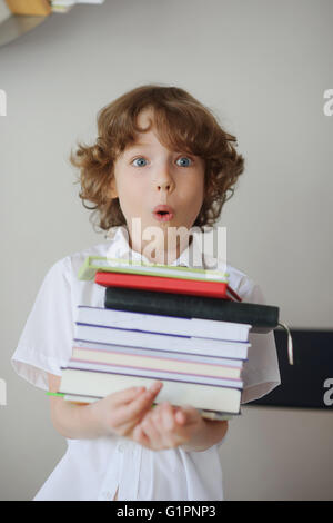 School child holding stack of books in classroom Stock Photo - Alamy