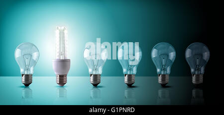 Energy saving concept with light bulbs sequence on a glass table. Led and incandescent bulbs on blue green background. Horizonta Stock Photo