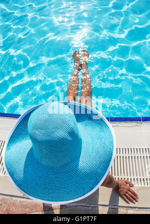 Woman sitting on the edge of swimming pool. Stock Photo