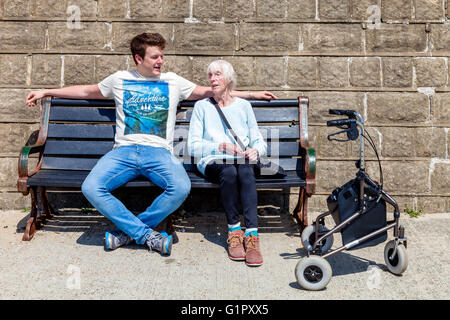 An Elderly Disabled Woman Sitting On A Bench Talking To Her Grandson, Brighton, Sussex, UK Stock Photo