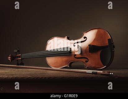 Old violin on a rustic wooden table with bow still life, arts and music concept Stock Photo