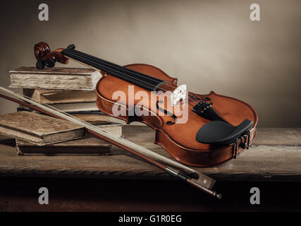 Old violin, bow and books on a rustic wooden table, still life Stock Photo