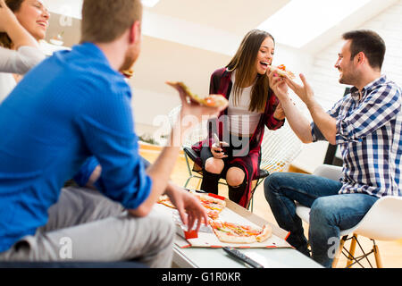 Group of friends eating pizza together at home Stock Photo