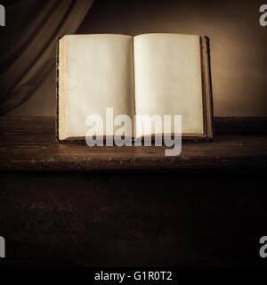 Open ancient book on an old wooden table, knowledge and literacy concept Stock Photo