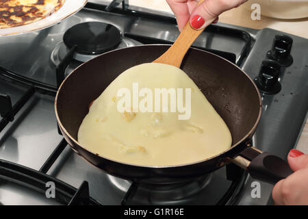 Woman's hands turning pancake by wooden trowel photo Stock Photo
