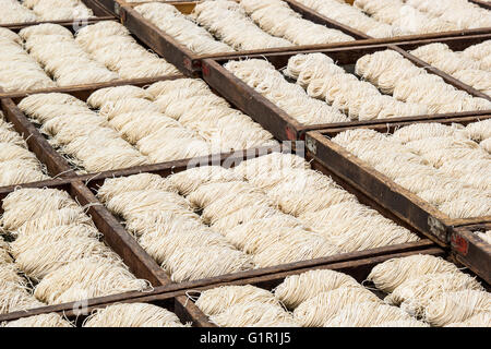 White chinese noodles in wooden trays drying outdoor under the sun Stock Photo