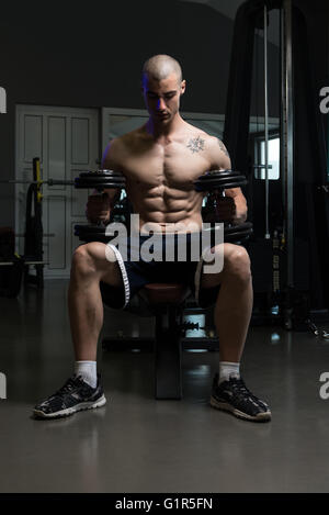 Portrait Of A Physically Fit Young Man In A Healthy Club With Dumbbells Stock Photo