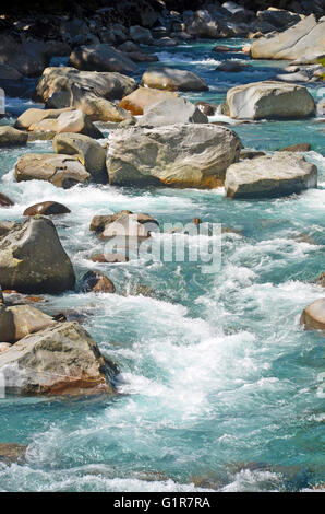 Crystal clear alpine mountain river with rapids flowing around boulders Stock Photo