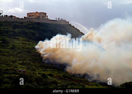 Forest fire in Greece, fire department spraying water from a hotel on a hill Stock Photo