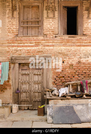 Typical facade of a two storey village house with wooden door and windows on brick wall. Stock Photo