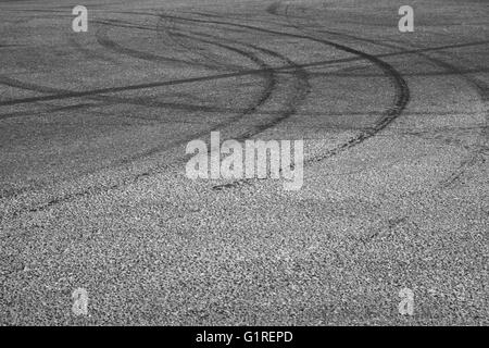Abstract transportation background with dark tire tracks on gray asphalt road Stock Photo