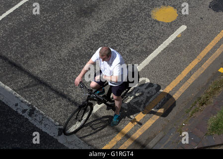 middle aged man cyclist  bike looking at watch on a  city corner  traffic light waiting viewed from above, Glasgow, Scotland, UK Stock Photo