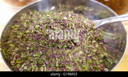 Green and lilac, dry seaweed on a spoon, in front of more colorful seaweed Stock Photo