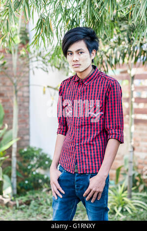 A portrait of a young trendy Burmese man with tanaka on his face, standing and looking straight into the camera, Bagan, Myanmar. Stock Photo