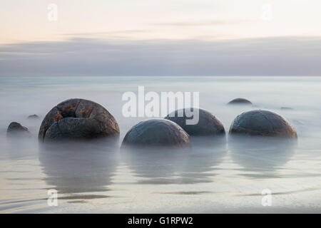 Moeraki Boulders on the Koekohe beach, New Zealand during sunrise (long exposure) Stock Photo