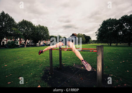 A woman is doing a planche on fitness equipment in the park Stock Photo