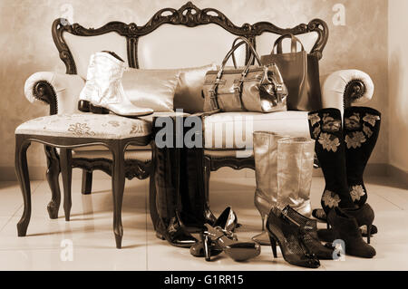 Female shoes, boots and handbags on a background of a sofa with pillows Stock Photo