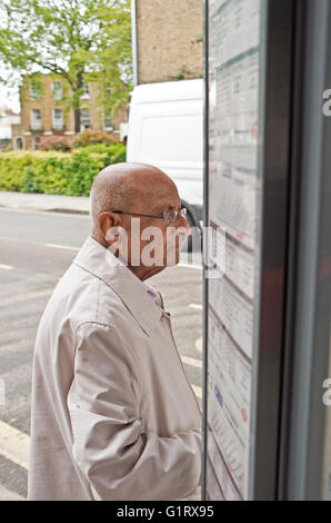 An elderly gentleman waits at a bus stop in London. Stock Photo