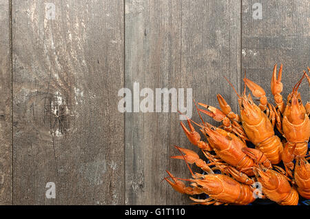 Plate of red crayfishes on old wooden table in left-bottom corner Stock Photo