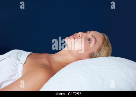 Side view shot of young woman lying on massage bed. Beautiful woman waiting for her spa treatment to begin. Stock Photo