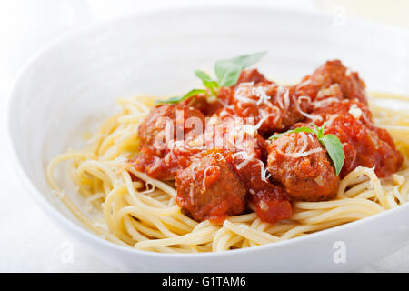 Meatballs in tomato sauce and fresh basil with spaghetti on a white plate Stock Photo