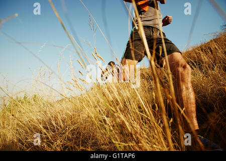 Man running through tall grass on sunny trail Stock Photo