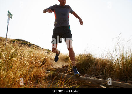 Male runner descending trail hillside Stock Photo