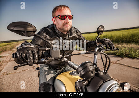 Biker in a leather jacket riding a motorcycle on the road. Filter applied in post-production. Stock Photo