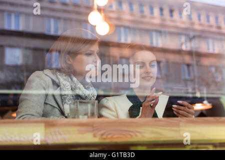 Businesswomen using cell phone at cafe window Stock Photo