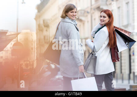 Portrait of smiling women with shopping bags on city sidewalk Stock Photo