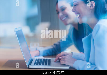 Laughing businesswomen working at laptop Stock Photo