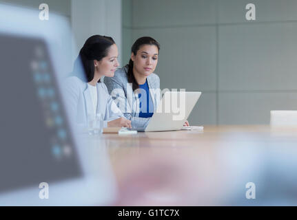 Businesswomen working at laptop in conference room Stock Photo