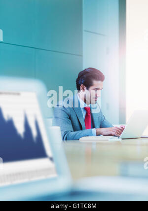Businessman typing on laptop in conference room Stock Photo