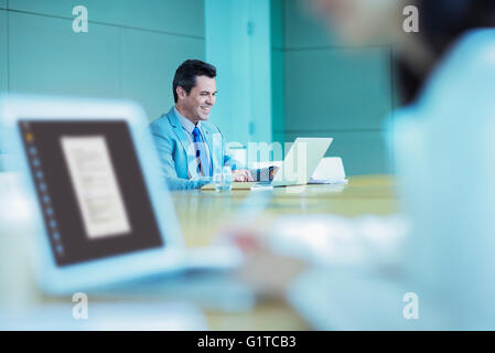 Smiling businessman working at laptop in conference room Stock Photo