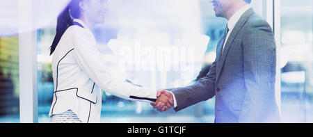 Businessman and businesswoman handshaking in office Stock Photo