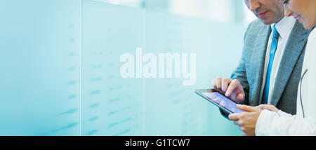 Businessman and businesswoman using digital tablet in office corridor Stock Photo