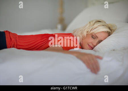 Serene woman sleeping on bed with eyes closed Stock Photo
