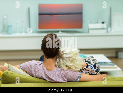 Relaxed couple watching TV on living room sofa