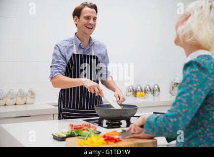 Smiling couple cutting and cooking vegetables in kitchen Stock Photo