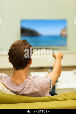 Man watching TV changing channels on living room sofa Stock Photo