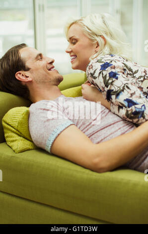Affectionate couple laying on living room sofa face to face Stock Photo