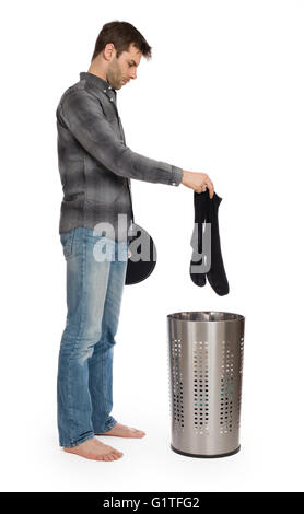 Young man putting a dirty socks in a laundry basket, isolated Stock Photo