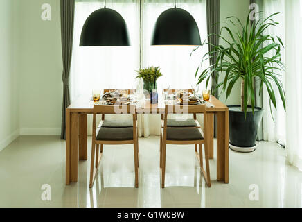 dining table and comfortable chairs in modern home with elegant table setting Stock Photo