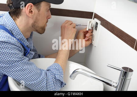 A Electrician changing a socket outlet in bathroom Stock Photo