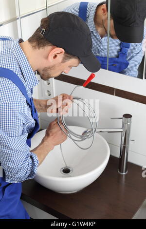 A Plumber cleaning a pipe drain with a Spiral Stock Photo