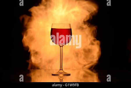 single glass with red wine on fire background isolated black Stock Photo