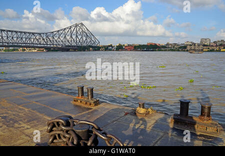 Passenger vessels and jetty on Hooghly river, with Howrah Bridge at background, Kolkata, West Bengal, India Stock Photo